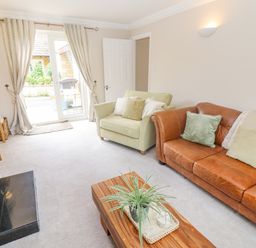 A living room with a green armchair brown leather sofa and wooden coffee table at The Cornerstone in Bourton-On-The-Water