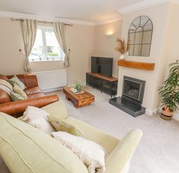A living room with sofas a coffee table a television a fireplace and a plant at The Cornerstone in Bourton-On-The-Water