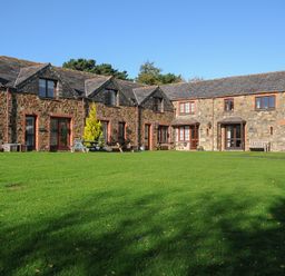 Stone cottages with slate roofs and green lawn in front at The Snug in St Minver