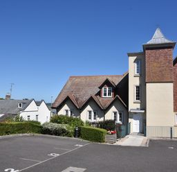 A parking lot with numbered spaces in front of a multi-section building with pitched roofs and multiple windows at 1 Buckfields in Lyme Regis