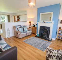 A living room with sofas a fireplace and a dining area with chairs in the background at 4 The Cloisters in Bushmills County Antrim
