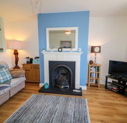 A living room with a fireplace television sofa and lamps at 4 The Cloisters in Bushmills County Antrim