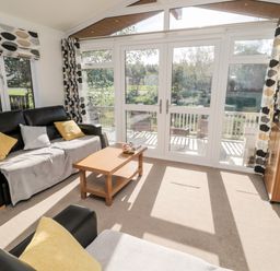 A living room with two black sofas and a wooden coffee table near large glass doors at Pinecone Lodge - No 9 Felmoor Park near Felton