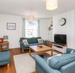 A living room with blue sofas wooden coffee table and television at Navigators Rest in Whitby