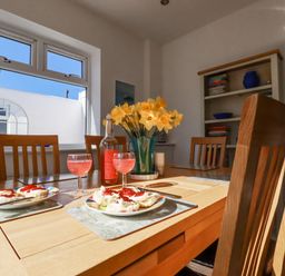 A dining table set with plates of scones with jam and glasses of pink drink in a dining room at Sea View in Mevagissey