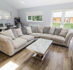A living room with a large sectional sofa and a marble coffee table at Lodge 32 in Otterburn