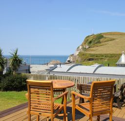 A wooden table and chairs overlooking the sea at 11 Cove View Apartments Ilfracombe