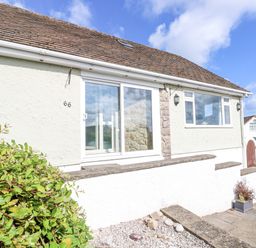 The exterior of a single story house with sliding glass door a window a tiled roof and plants in front at Treestumps in Benllech