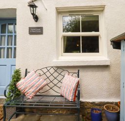 An outdoor seating area with a bench and cushions at Gwynn Cottage St Mabyn
