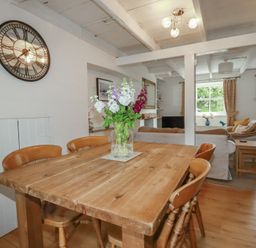 A dining room with a wooden table and chairs at Gwynn Cottage St Mabyn