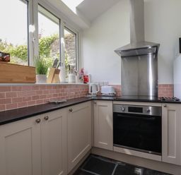 A kitchen with modern appliances and a window at Gwynn Cottage in St Mabyn