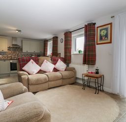 A living room with a sofa and kitchen units at Top Lodge in Llanvair-Discoed near Penhow