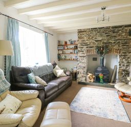 A living room with leather sofas a stone fireplace and bookshelves at The Old Post Office in Llanelian near Old Colwyn