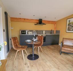 A kitchen area with table and chairs a microwave and toaster on counter and a framed picture on the wall at Rhosyn in Llangadfan