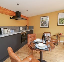 A kitchen and dining area with a wooden table set for two and leather chairs at Rhosyn in Llangadfan