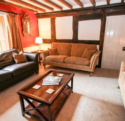 A living room with patterned sofas a leather sofa a wooden coffee table and a lamp at Pentre Hall in Bronygarth near Chirk