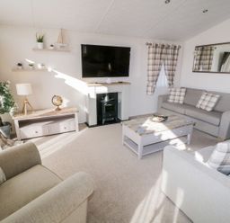 A living room with sofas a coffee table a television and a lamp at Rockpool Retreat in Runswick Bay near Hinderwell