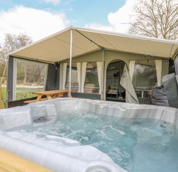 A hot tub outside a tent with a picnic table in a grassy area at The Salmon in Nantmel near Rhayader