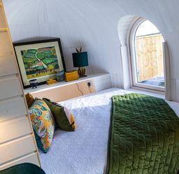 A bedroom with a bed with a green blanket and pillows next to an arched window at Veiko - Mayflower Meadow in Burshill near Brandesburton