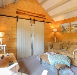 A living room with wood paneled walls a sofa and a tv at Willow Lodge in Potter Heigham