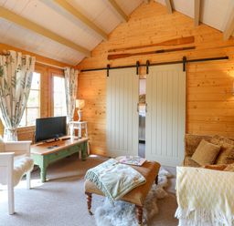 A wooden living room with seating a television and sliding doors at Willow Lodge in Potter Heigham