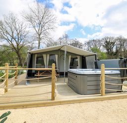 An outdoor wooden deck with a hot tub and a covered tent with a picnic table at The Otter in Nantmel near Rhayader