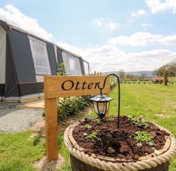 A garden bed with a lantern and a wooden sign that says Otter near a tent structure at The Otter in Nantmel near Rhayader