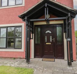 A front entrance with a dark wood door and black framed porch at 9 Eamont Park in Penrith