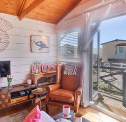 A living room with a leather armchair near a window and wooden furniture at Sea Spray in Lyme Regis