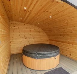 A wooden room with a covered round hot tub and a small floor mat at Laird Lodge 2 in Lochmaben