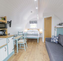 A compact living space with a kitchen area dining table bed and sofa at Laird Lodge 2 in Lochmaben