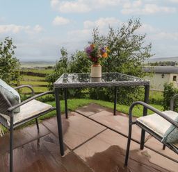 An outdoor seating area with a table and chairs at The Herdsman Luxury Shepherds Hut in Barnoldswick