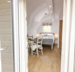 A bedroom with a double bed a small table with two chairs and wooden flooring at Laird Lodge 4 Lochmaben