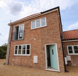 A brick exterior of a two-story house with multiple windows and an open door at Jolly Sailors Retreat - Wells next the Sea in Wells-Next-The-Sea