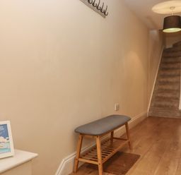 A hallway with a wooden bench and carpeted stairs at Mimosa in Dawlish