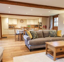 An open living area with a sofa coffee table dining table and kitchen at Little Orchard in Ashburton Down near Ashburton