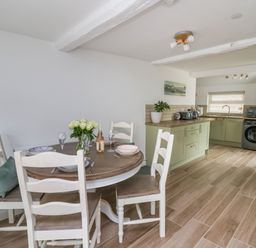 A kitchen and dining area with a round wooden table set for four and green cabinets at 2 Penporth in Rhayader