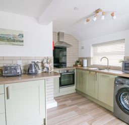 A kitchen with appliances including oven kettle toaster microwave washing machine and cabinets at 2 Penporth in Rhayader