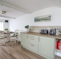 A kitchen and dining area with light green cabinets a round table and chairs at 2 Penporth in Rhayader