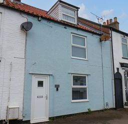 A row of terraced houses with a blue painted house in the center and white houses on either side at Bluebell Cottage in Flamborough