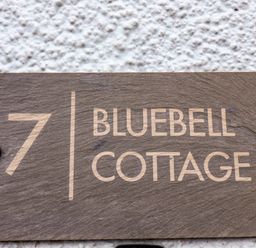 A house number 7 sign with Bluebell Cottage on a textured white wall at Bluebell Cottage in Flamborough