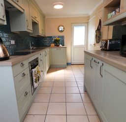 A kitchen with cabinets, a kettle, oven, toaster, microwave, and a door at 11 Penygroes in Llanddeusant