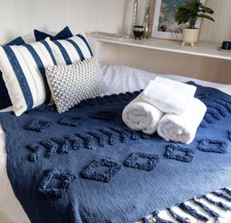 A bed with blue and white pillows folded towels and a blue textured blanket at Andrus - Mayflower Meadow in Brandesburton