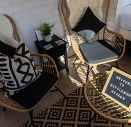 Two rattan chairs with cushions around a small glass table with welcome sign and black side table with plant in a room at Indrek - Mayflower Meadow in Brandesburton