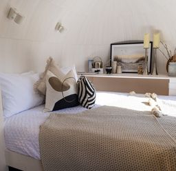 A bedroom with a bed and pillows next to a shelf with decor and a framed picture at Indrek - Mayflower Meadow in Brandesburton