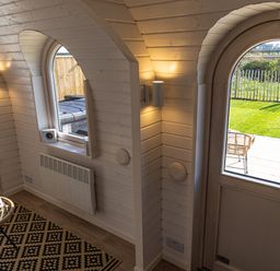 An interior room with a wooden arched door and window showing a garden outside at Indrek - Mayflower Meadow in Brandesburton