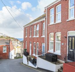 A street view of brick houses with windows and doors near a coastal area at Chy An Mor in Mevagissey