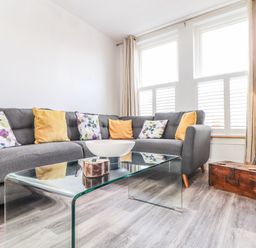 A living room with a gray sofa and glass coffee table near windows at Chy An Mor in Mevagissey