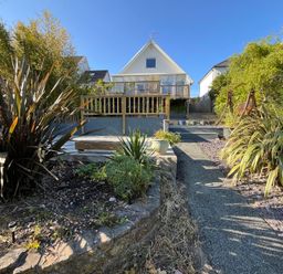 A garden with plants a pathway and a house with a balcony at Old Orchard in Saundersfoot