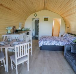 An open plan room with a dining table set for four a kitchenette a double bed and a sofa at Tamina in Hillhampton Great Witley